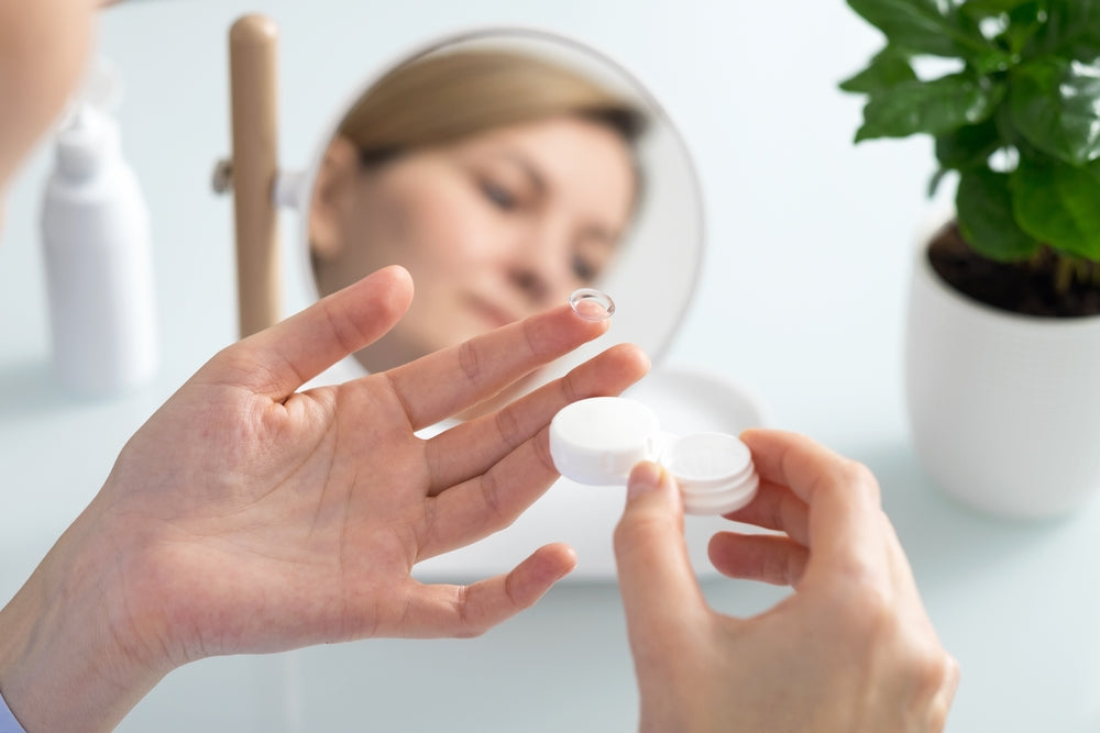 A woman gets ready to insert a contact lens into her eye